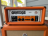 Orange OR50 guitar amplifier on a wooden surface with a blurred outdoor background