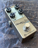 Pigtronix Philosopher's Tone German Gold Micro guitar effects pedal with four black knobs and a gold footswitch, photographed on a textured dark stone surface.