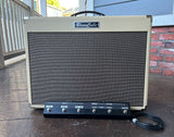 Tan Blues Cube guitar amplifier on a wooden deck with a brick wall in the background