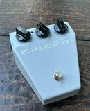 Grey Guitar effects pedal with  three knobs controls 'Eradicator' branding on a wooden surface
