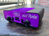 A purple and black T11D Hot Plate O8hm  amplifier sitting on a dark stone surface outdoors.