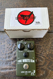 dark green Wren and Cuff guitar pedal with with three control knobs with packaging on a wooden surface